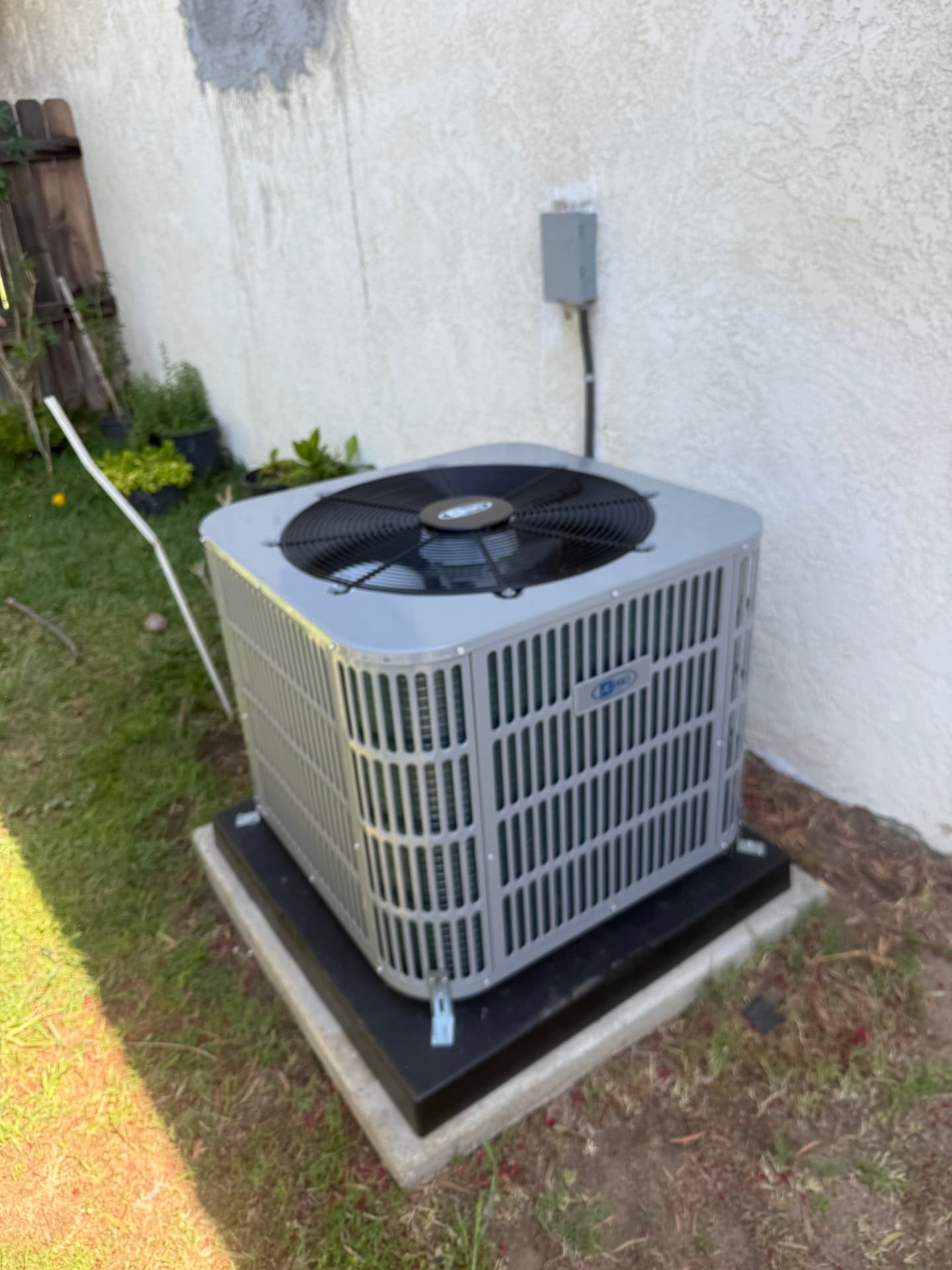 New outdoor AC condenser installed on a concrete pad beside a home in Upland, CA
